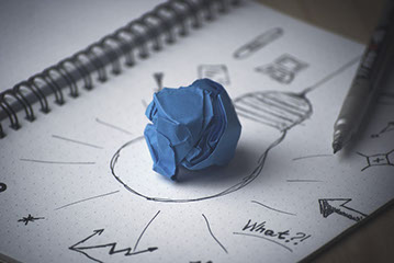 Bola de papel sobre el dibujo de una apolleta en un cuaderno